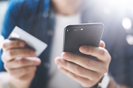 スマートフォンとクレジットカードを持つ人